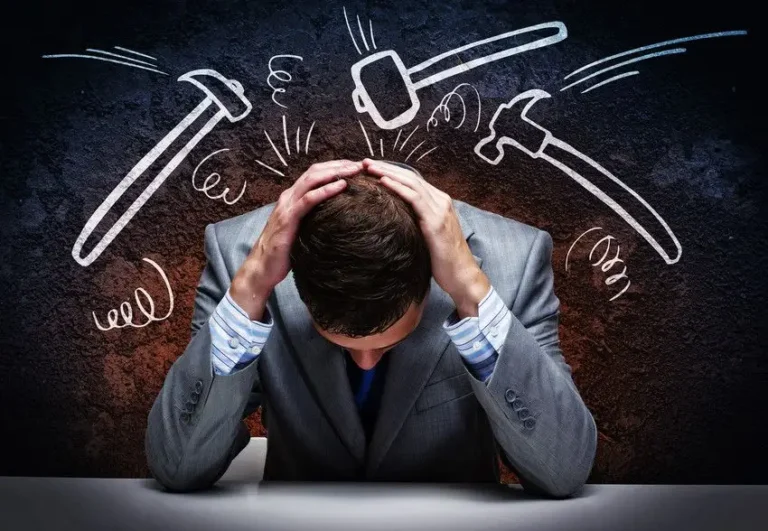 Stressed man with hands on his head and chalkboard behind him.