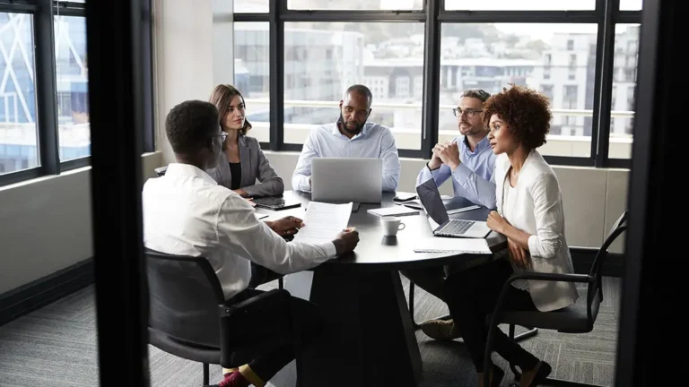 group of employees gathered around a table for a meeting