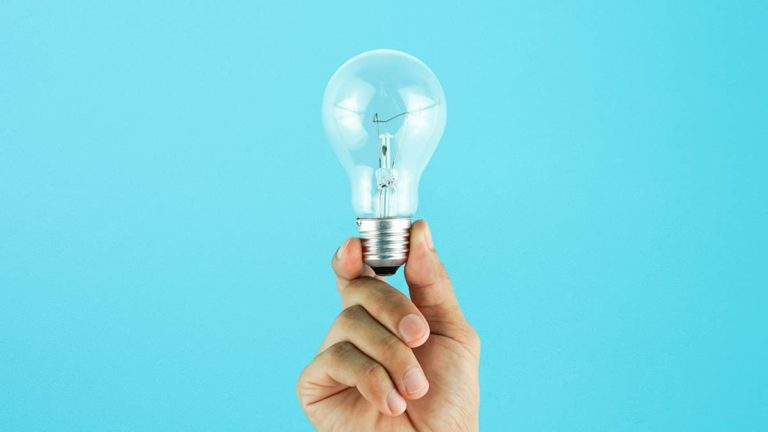 person holding lightbulb in front of blue background