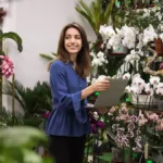 Flower shop worker using laptop in front of flowers