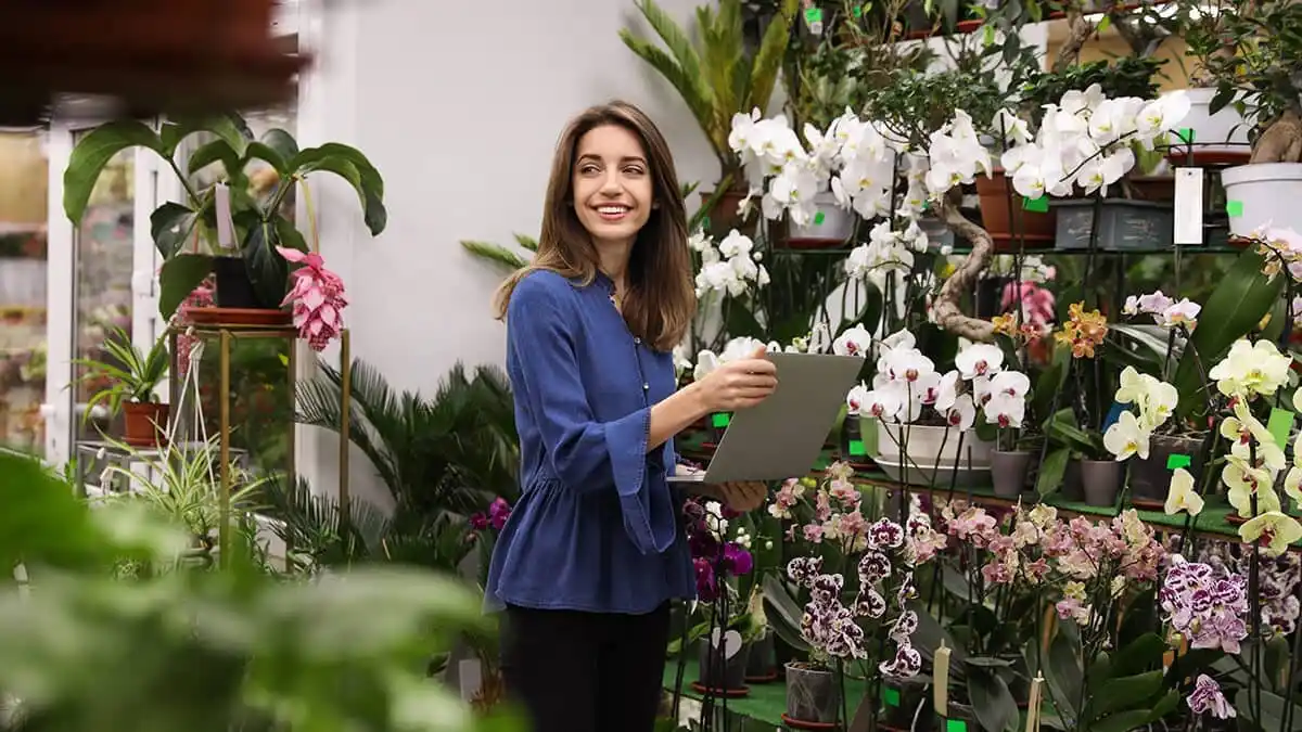 Flower shop worker using laptop in front of flowers