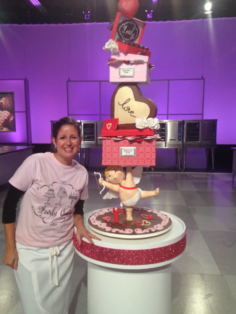 Renata Papadopolous stands next to her winning cake from Food Network's Cake Wars. 