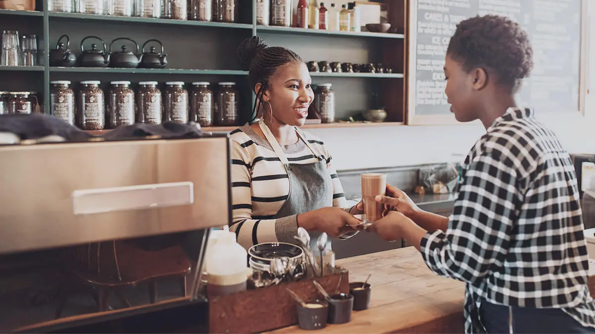 Barista handing a customer a latte.