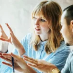 Co-workers discussing something on desktop screen.