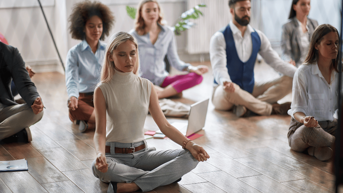 Employees meditating as they advantage of mental health initiatives in the workplace.